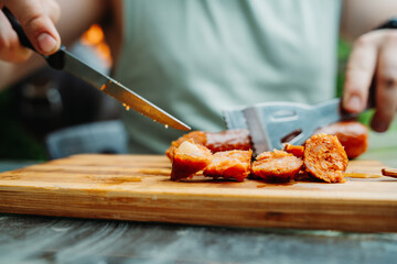 Close up of man hands cutting bbq sausage with knife