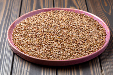 Buckwheat Grains on Plate on Wooden Background, Top View, Copy Space.Hulled kernels of buckwheat grains close up. Food background.