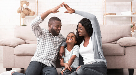 Adoption concept. African american foster family making symbolic roof of hands gesture above little...