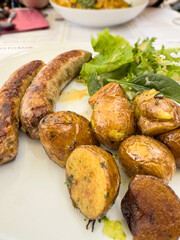 grilled sausages with potatoes and salad on plate