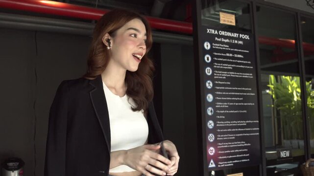 Business woman working outside picking up mobile with smart watch and talking with wireless earpods.