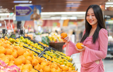 Portrait beauty asian happy woman relax and enjoy shopping time with trolley cart buy healthy food package of grocery food with clean vegan eating vegetable and fruit at shopping supermarket