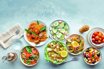 Fresh salads, overhead flat lay shot of an assortment. Variety of plates and bowls with green vegetables. Healthy food, top shot, with copy space