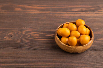 Pile of smoked quail eggs in bowl on a brown wooden. side view, copy space.