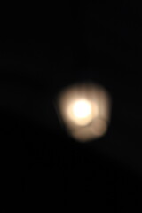 A blurry dreamy view of a street lantern glowing in the darkness.