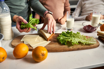 In the kitchen, laughter fills the air as a mother and her daughters enjoy breakfast, sharing bites and sandwiches. A delightful family meal.