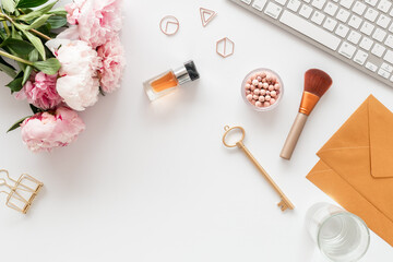 Office desk table with female supplies and pink peony, top view