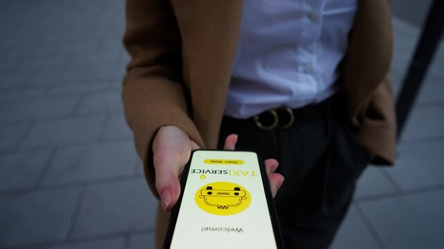 Closeup young businesswoman hands opening taxi app using mobile phone on go in the street