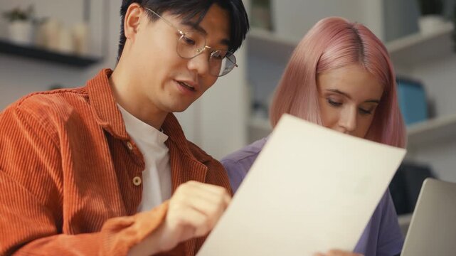 Happy multiracial couple calculating family budget on laptop, giving high five