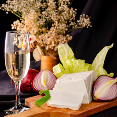 still life with cheese, onion and a glass of white wine on a black background