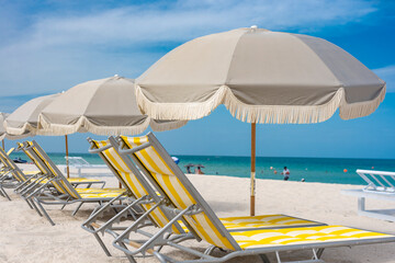 Light gray parasol and yellow Chaise lounges by the beachfront at Miami Beach.