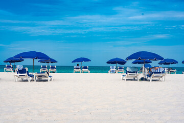 Blue parasols and chaise lounges facing the beach. At Miami Beach, Florida.