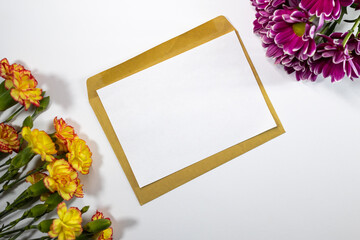Yellow and pink flowers on white background and with envelope in the center. Space for inscriptions, congratulations. Carnations and chrysanthemums