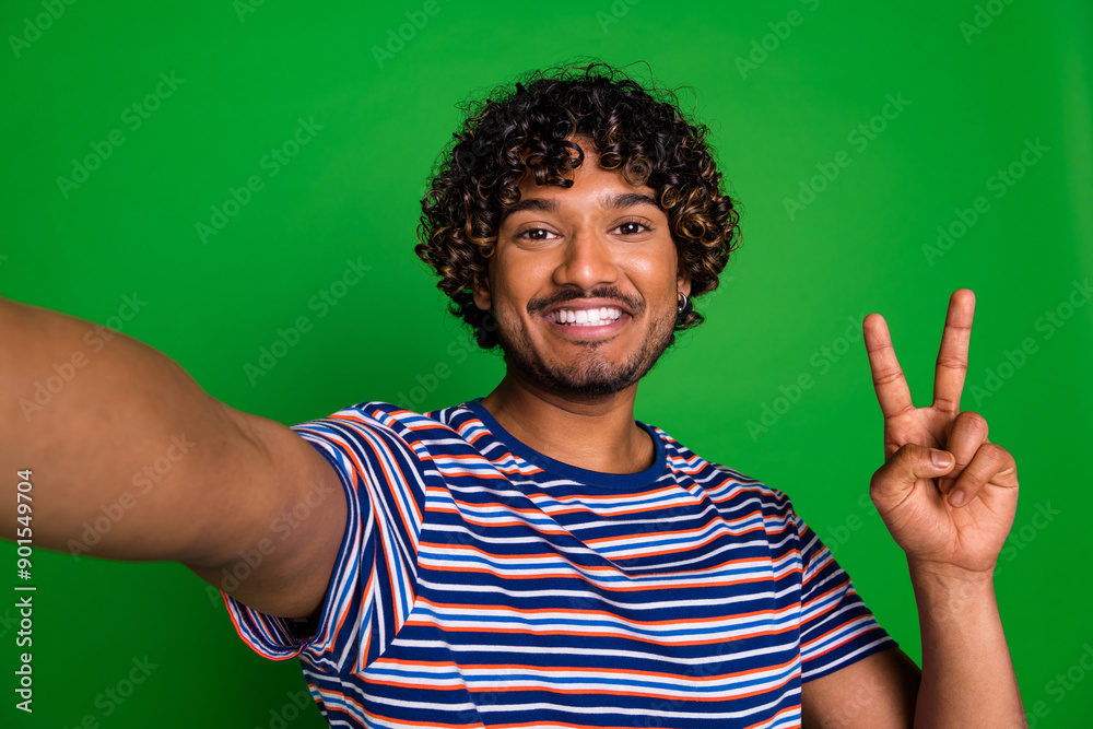 Sticker Photo of cool positive nice man wear trendy striped clothes video live stream v-sign isolated on green color background