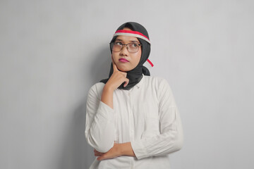 Thoughtful Young Woman in White Shirt and Black Headscarf with a Red and White Ribbon