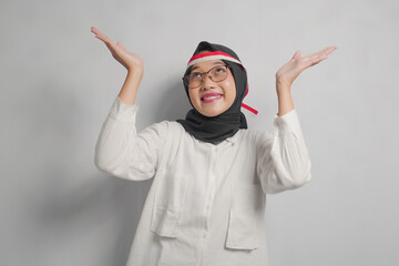 Smiling Woman with Headscarf and Glasses Gesturing Upwards