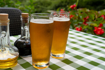 Two beer glasses at outdoor cafe, cold pint glass on checkered tablecloth table, cool condensation