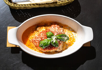 Lasagna portion, oven baked lasagne, pasta layers with cheese, minced meat, tomato in sunny summer day