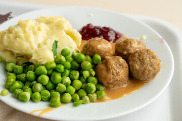Meatballs with french fries, green peas, bechamel sauce and cranberry jam, meat balls on white plate