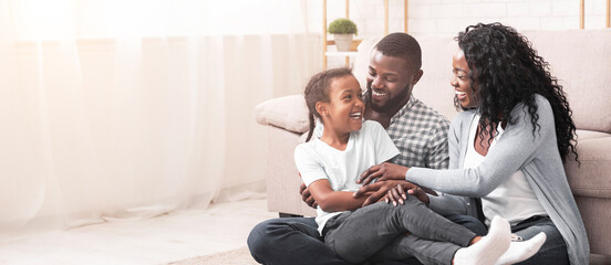African american family having fun at home, parents tickling their daughter and laughing together.