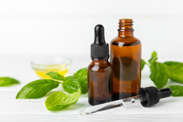 Basil essential oil on a textured wooden background. Basil essential oil and fresh leaves. Aromatherapy. Aroma oil. Medical herbs. Alternative medicine. Place for text. Copy space.