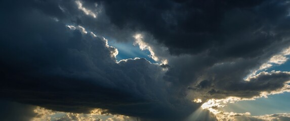 Dramatic sky with rays of light piercing through dark clouds evoking a sense of awe and the sublime beauty of nature.