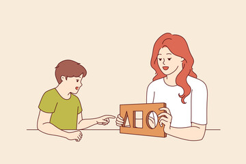 Woman child psychologist tests preschool boy, checking child intelligence and mental health. Child psychologist works with child, diagnosing problems in early stages of upbringing.