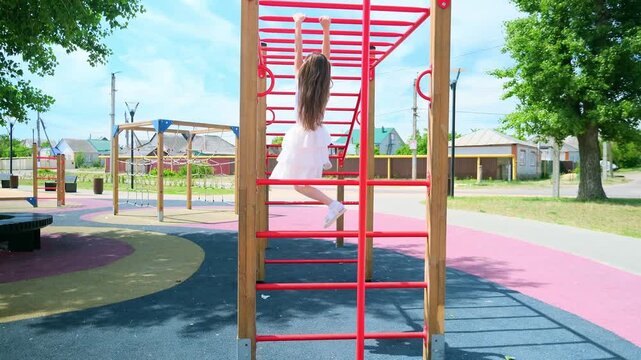 Child playing on outdoor playground. Kids play on school or kindergarten yard. Active kid on colorful monkey bars. Healthy summer activity for children. Little girl climbing.