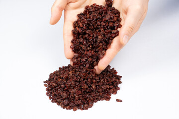 Red dried barberry natural seasoning pouring out of human hands on white background