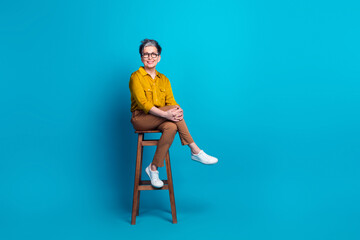 Full length photo of pretty cheerful woman wear shirt spectacles sitting chair emtpy space isolated...
