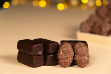 Chocolates in the shape of Christmas figures on the background of a flashing garland