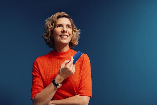 Mature woman holding a credit card in a vibrant, monochromatic setting with bold colors