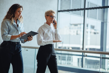 Morning briefings: Executive assistant walks behind her boss in a busy business office