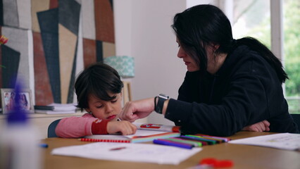 Naklejka premium Mother offering guidance while young boy expresses frustration during homework, colorful educational materials on the table, depicting the challenges and support in home learning