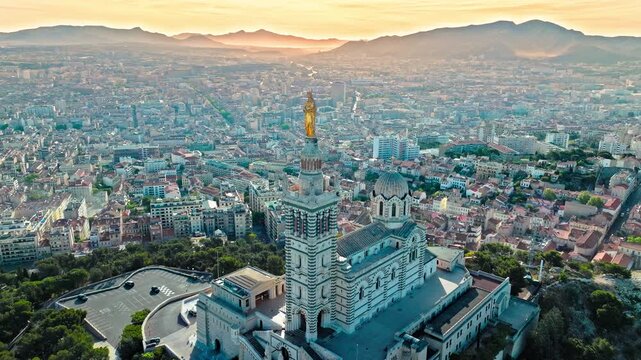 Grand basilica on top of a hill crowned by a golden statue, old city centre and port by blue Mediterranean sea coast in Marseille, France. Basilica of Notre Dame of la Garde at Marseille in France.