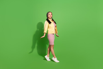 Full body portrait of pretty young woman stand tiptoe wear jacket dress isolated on green color background