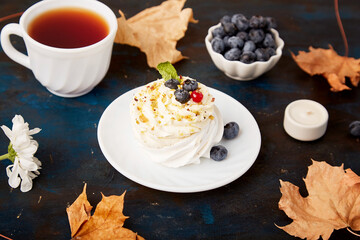 Traditional Pavlova Dessert with Tea Cup and blueberry. Autumn tea time vibes background. Hygge aesthetics