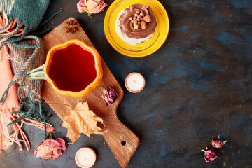 Aesthetic Pavlova chocolate cake, Tea Cup in shape of pumpkin. Autumn aesthetics tea time vibes flat lay among dry roses, leaves. Copy space