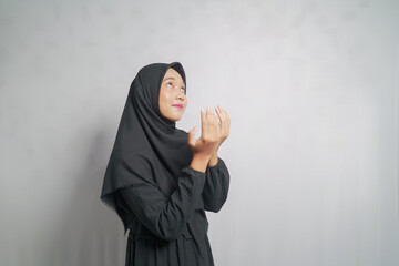 Woman in black hijab looking up with hands raised