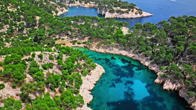 Aerial view of Natural area with rock formations, turquoise water beach in France. Calanque de Port Pin beach in the eastern calanque between Marseille and Cassis.
