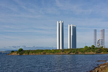 Wind Turbine Towers upright and waiting for onward transportation at the Port of Dundee, with a Jack Up oil Rig in the background.
