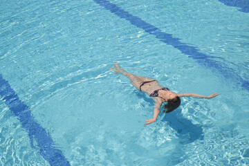 Young woman floating in the large resort swimming pool