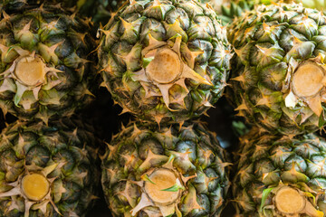 Close up of fresh pineapples displayed in fruit market stacked together. Food texture and pattern. Abstract background