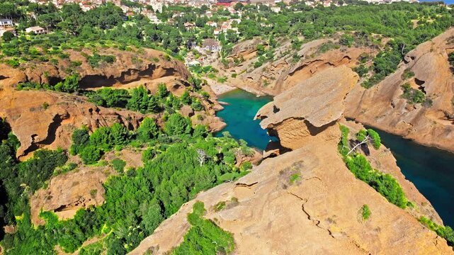 Aerial view of Tourist attraction beach, people enjoying summer vacation in Parc du Mugel, France. Snug Cove framed by rugged cliffs, with calm swimming off a pebble beach, and turquoise clear water.