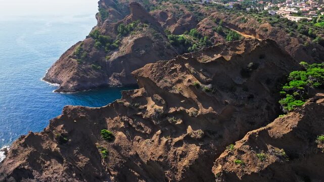 Aerial view of Tourist attraction beach, people enjoying summer vacation in Parc du Mugel, France. Snug Cove framed by rugged cliffs, with calm swimming off a pebble beach, and turquoise clear water.