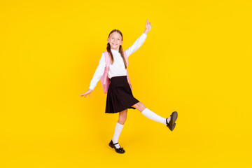 Full length photo of lovely small schoolgirl back school celebrate dance dressed stylish uniform isolated on yellow color background