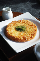 kunafa with a wipe cream on a plate .