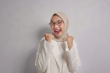 A Happy Woman in a White Blazer and Hijab with Fists Raised