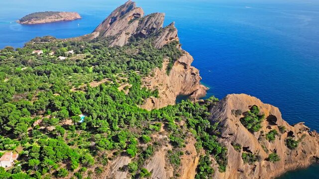 Aerial view of a Botanical garden with Snug Cove framed by rugged cliffs in Parc du Mugel. View from above of swimming off a pebble beach with turquoise clear water in France.