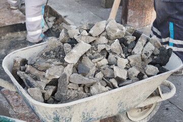 A group of construction workers moving a wheelbarrow loaded with rubble on a construction site